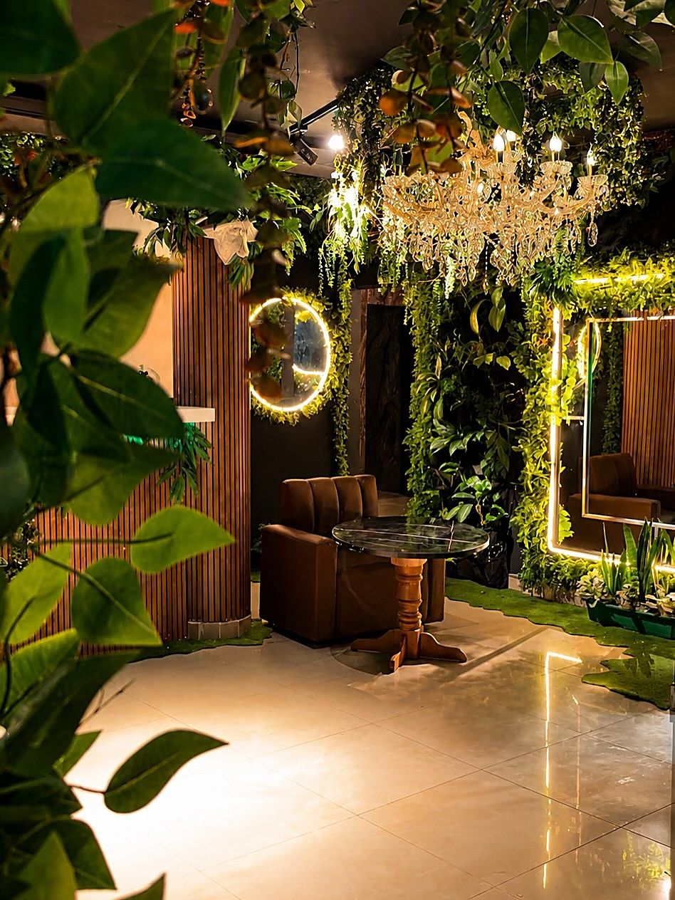 Rincón de Selva Negra con una lámpara de cristal, un espejo con aro de luz y una sala entre plantas