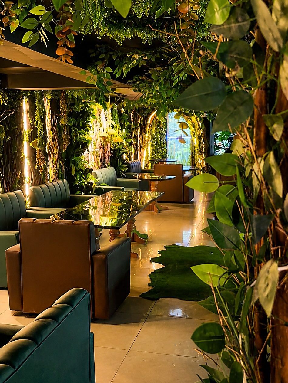 Salas con sofás verdes y mesas de mármol, entre plantas y luces tibias, en Selva Negra