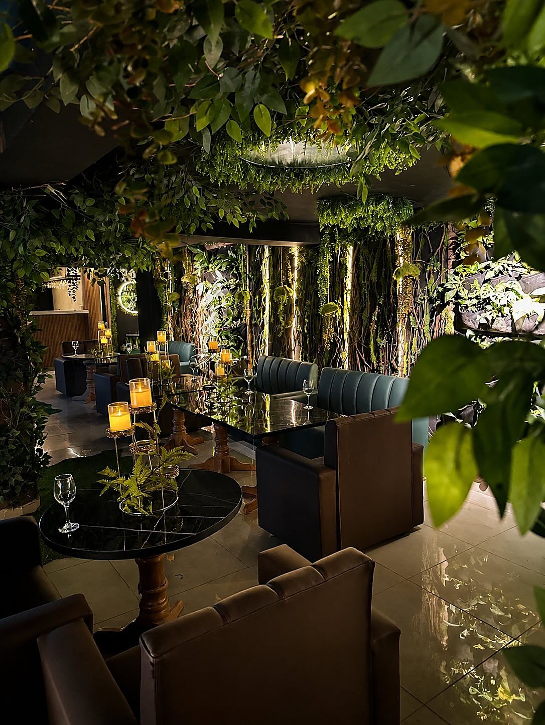 El salón de Selva Negra de noche, con velas sobre las mesas y hojas colgando del techo